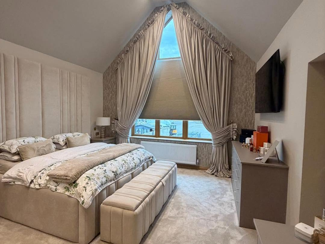 Shaped apex pleated blind with curtains in bedroom